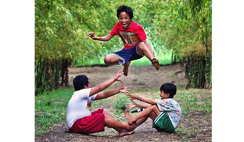 Three children playing Filipino traditional game Luksong Tinik